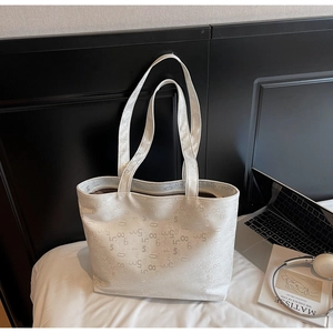 Detail of white large capacity tote bag with embossed text pattern on white bedding