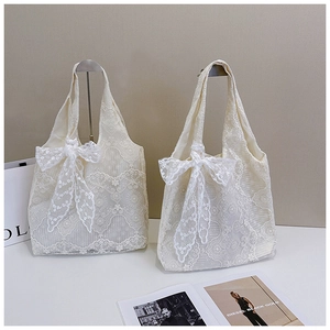 Close-up of cream lace tote bags featuring delicate floral patterns and large bow details
