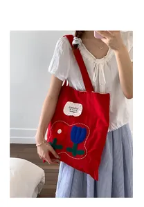Detail of red canvas tote bag featuring floral embroidery and large capacity for women