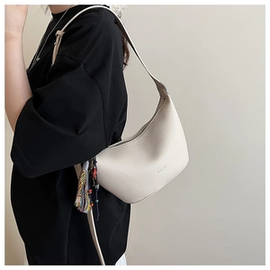Détail du sac croissant en cuir beige avec pompon ethnique coloré et perles