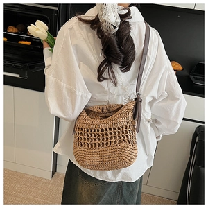 Detail of hand-woven straw bag with hollow mesh design and adjustable leather strap