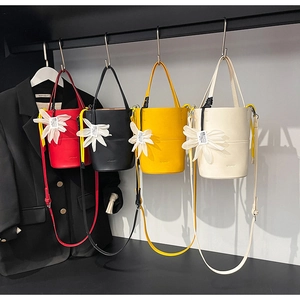 Detail showing four bucket bags in red black yellow white with daisy charm accessories