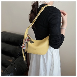 Détail du sac croissant jaune avec texture cuir et breloque à pompon coloré chic