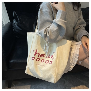 Gros plan sur un sac cabas en toile avec cordon fleuri et inscription hello en rouge