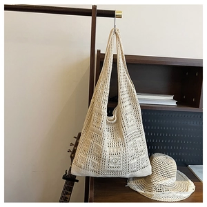 Detailed macro view of cream-colored crochet hobo bag with geometric hollow weave pattern