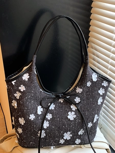 Elegant black tote bag with 3D floral appliques and bow detail in soft natural light