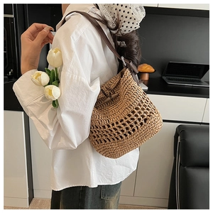 Detail of straw bucket bag featuring vintage horn button closure and leather strap