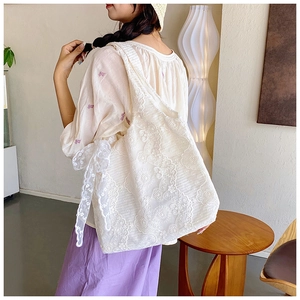 Detail of white floral lace tote bag with bow accent and spacious interior structure