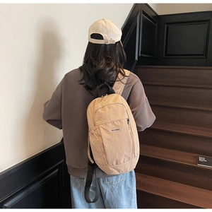 Detailed view of lightweight khaki nylon backpack with unique crinkle texture and logo