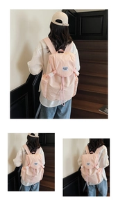 Détail du sac à dos en nylon rose avec cordon, rabat et écusson logo blanc brodé