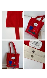Close-up of red canvas tote bag with floral embroidery and be fearless inspirational quote