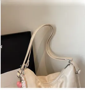 Close-up of cream-white pleated tote bag with silver zipper and pink heart charm