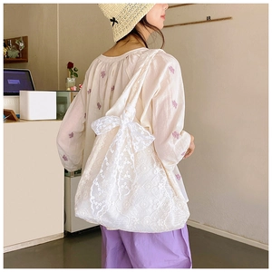 Detailed shot of white floral lace tote bag featuring a large decorative side bow accessory
