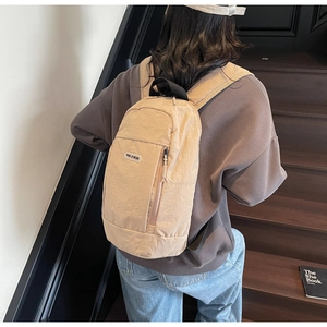 Beige nylon backpack shown on model with subtle wrinkled texture and side hidden pocket