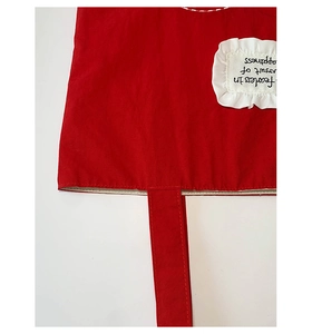 Detail of red canvas tote bag with white ruffle label and embroidered fearless quote