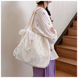 Detailed side view of white lace tote bag featuring floral embroidery and big bow decoration
