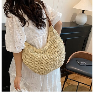 Detail of elegant beige straw hobo bag featuring fine weave and brown leather strap