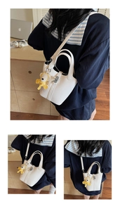 Detalle del bolso cubo de cuero blanco con un tierno colgante de oso amarillo