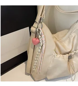 Detail view of cream hobo bag with ruched closure and decorative heart charm