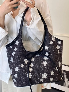 Retro black tweed tote bag with white floral pattern and ribbon detail on model