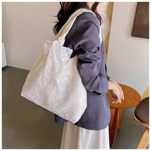 Detailed shot of white floral lace tote bag with large decorative bow on the shoulder strap