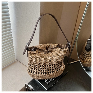 Detail of straw shoulder bag with leather strap and horn toggle closure in summer setting