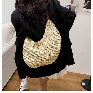 Detail of handwoven beige straw hobo bag with brown leather strap and texture