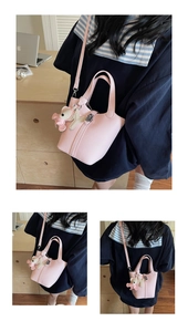 Detalle del bolso tipo cubo en cuero rosa con colgante de oso y correa ajustable