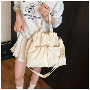 Detail of off-white canvas tote bag featuring drawstring closure and two front pockets