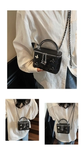 Detail view of mini black box bag with silver butterfly accents and chain strap