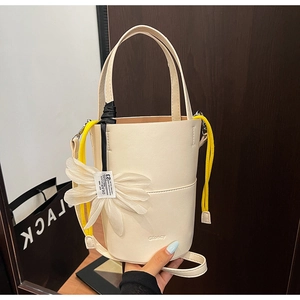 Detailed macro view of a cream-white bucket bag with floral motifs and yellow drawstrings