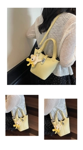 Detalle del bolso bombonera de cuero amarillo con asa superior y colgante de oso