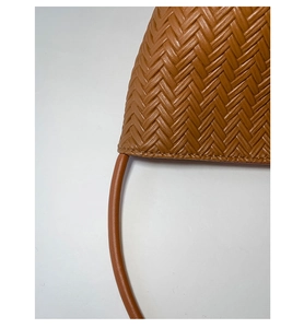 Close-up of tan woven texture and premium leather handles on casual tote bag