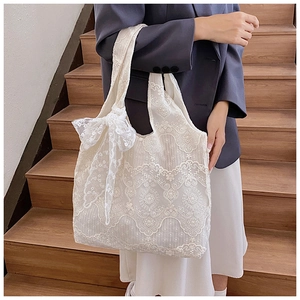 Detail of white crochet floral lace tote bag featuring a large side bow decoration