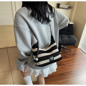 Detail of knit hobo bag with black stripes and leather strap on model shoulder