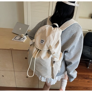 Vue détaillée d'un sac à dos blanc cassé élégant avec fermeture à rabat et poche latérale zippée