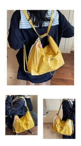 Detail of yellow pleated shoulder bag with heart pendant and drawstring side pocket