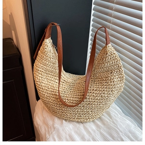 Detail of the straw hobo bag showing the woven texture and brown leather strap