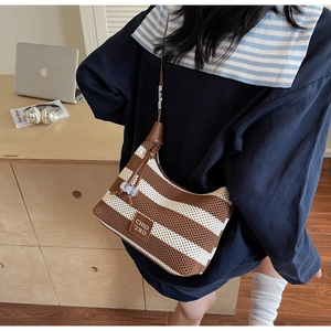 Detailed view of the striped woven shoulder bag with a brown leather logo patch