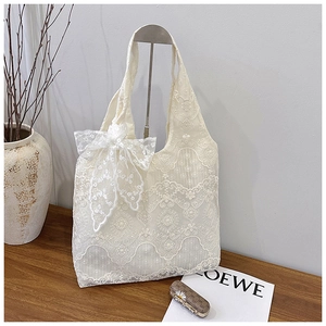 Close-up of white lace tote bag featuring floral embroidery and a large decorative bow