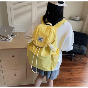 Détail du sac à dos en nylon jaune avec fermeture à boucle et cordon de serrage