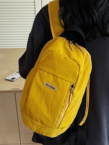 Minimalist yellow nylon sports backpack for women showing side view in a cozy indoor setting