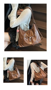 Detail of a dark brown pleated tote bag with heart charm on an indoor wooden staircase