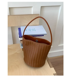Detailed view of woven brown bucket bag with magnetic closure and PU leather texture