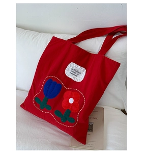 Detail of red canvas tote bag with floral embroidery and be fearless inspirational text