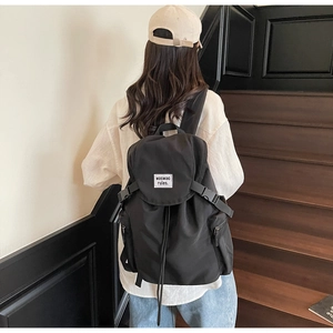 Détail du sac à dos noir en nylon avec écusson blanc et fermeture par cordon de serrage