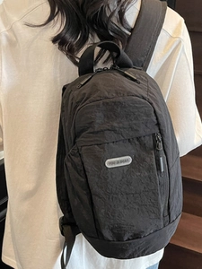 Minimalist black crinkled nylon backpack for women on model at indoor stairs