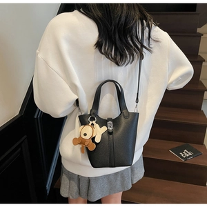 Bolso tipo cubo de cuero negro con cierre plateado y detalles de colgantes suaves