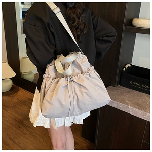 Rear view of a model wearing a slouchy grey drawstring tote bag with thick white straps