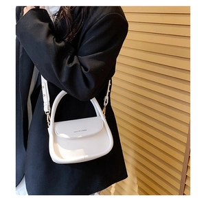 Detail of white saddle bag with magnetic closure and gold hardware on model's side